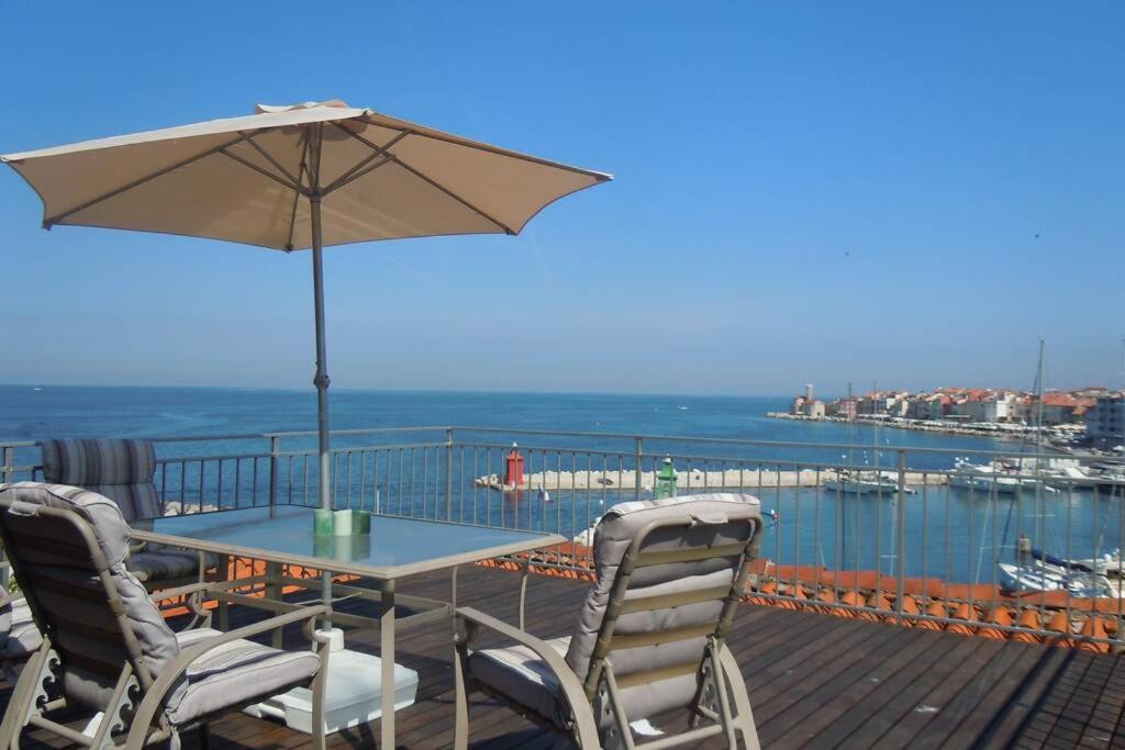 a table and chairs with an umbrella on a deck at Unique spacious apartment with terrace in Piran