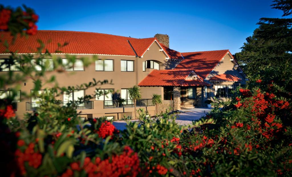 un bâtiment avec des toits rouges et des fleurs au premier plan dans l'établissement Hotel Provincial, à Sierra de la Ventana
