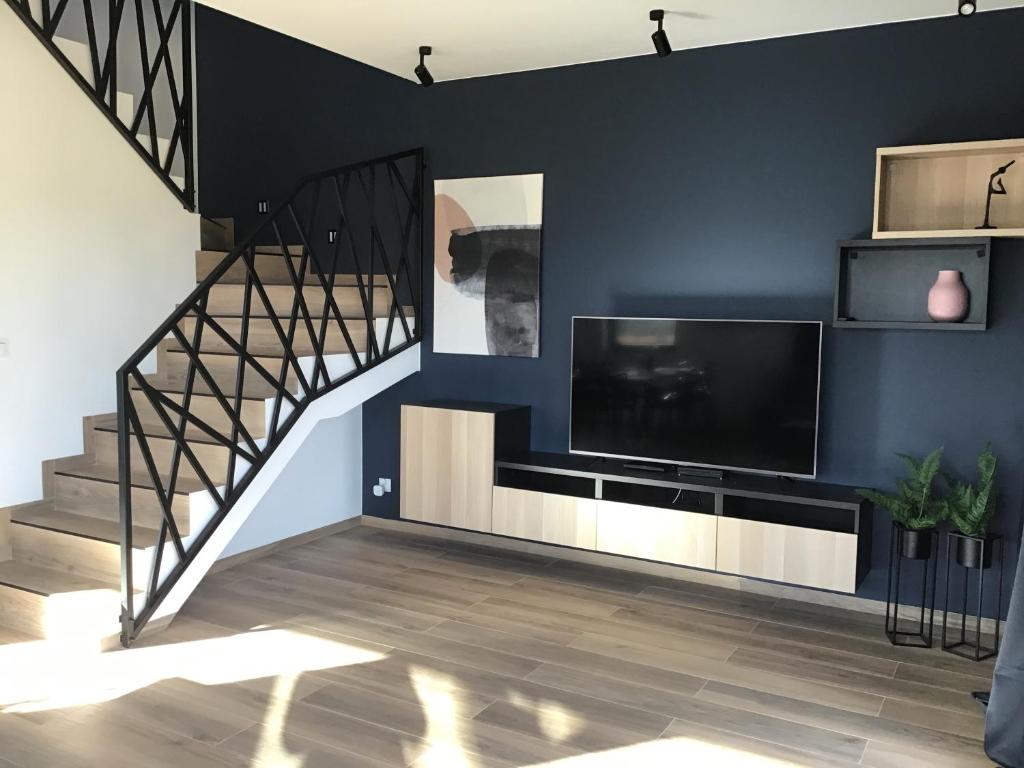 a living room with a staircase and a flat screen tv at Slow Life Apartment Mechelinki in Mechelinki