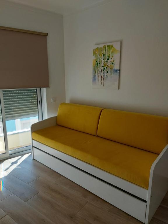 Sofá amarillo en una habitación con ventana en CASA BIA, en Portimão