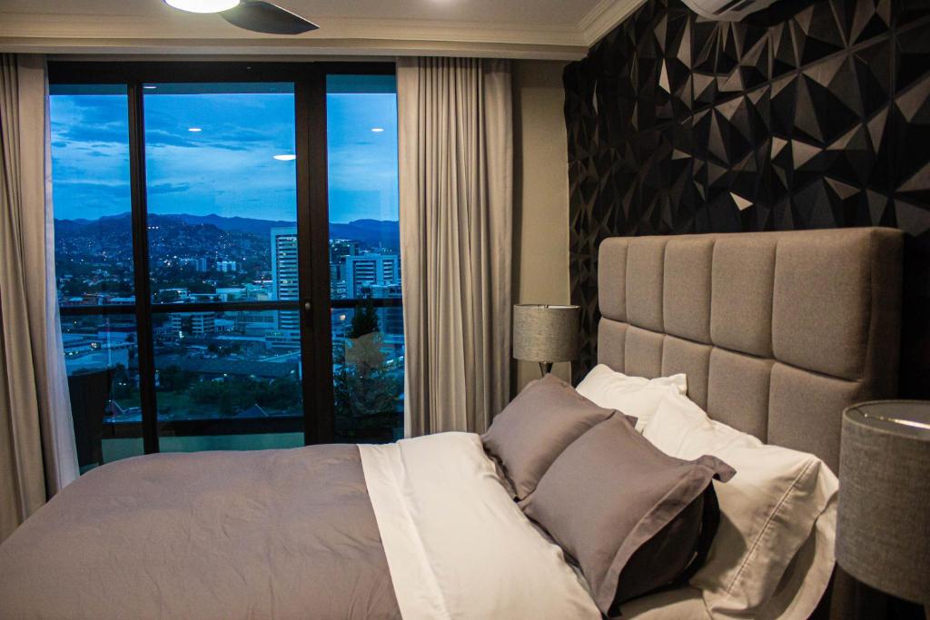 a bedroom with a bed and a large window at JF Apartments in Tegucigalpa