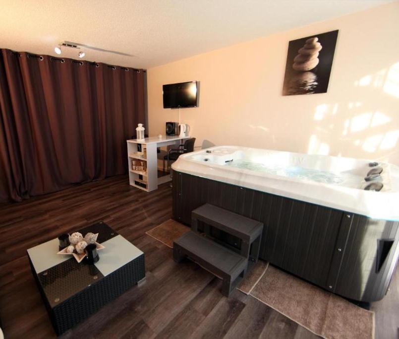 a bathroom with a large tub with a table and a table at Jac-Cosy in Fleurier
