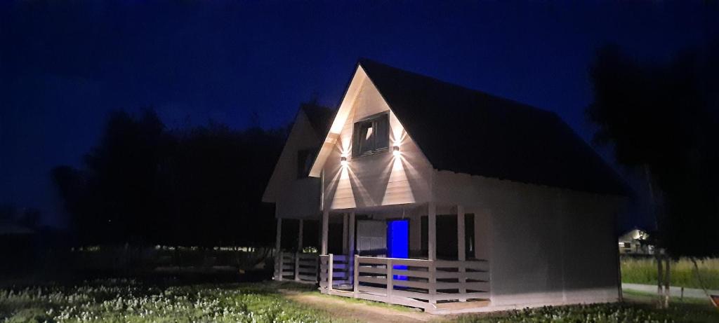 Una pequeña casa blanca con una luz azul. en San Escobar Dziwnówek en Dziwnówek