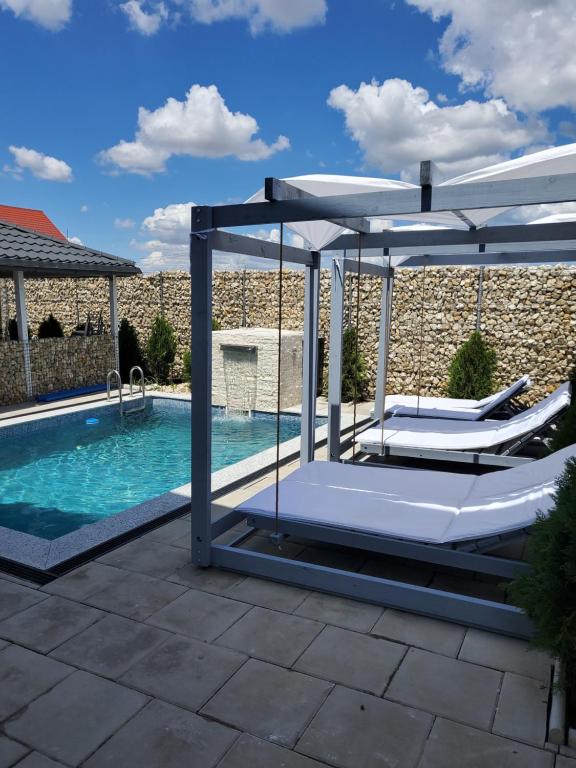 a pool with two lounge chairs and an umbrella at Vila Paradis Costinesti in Schitul