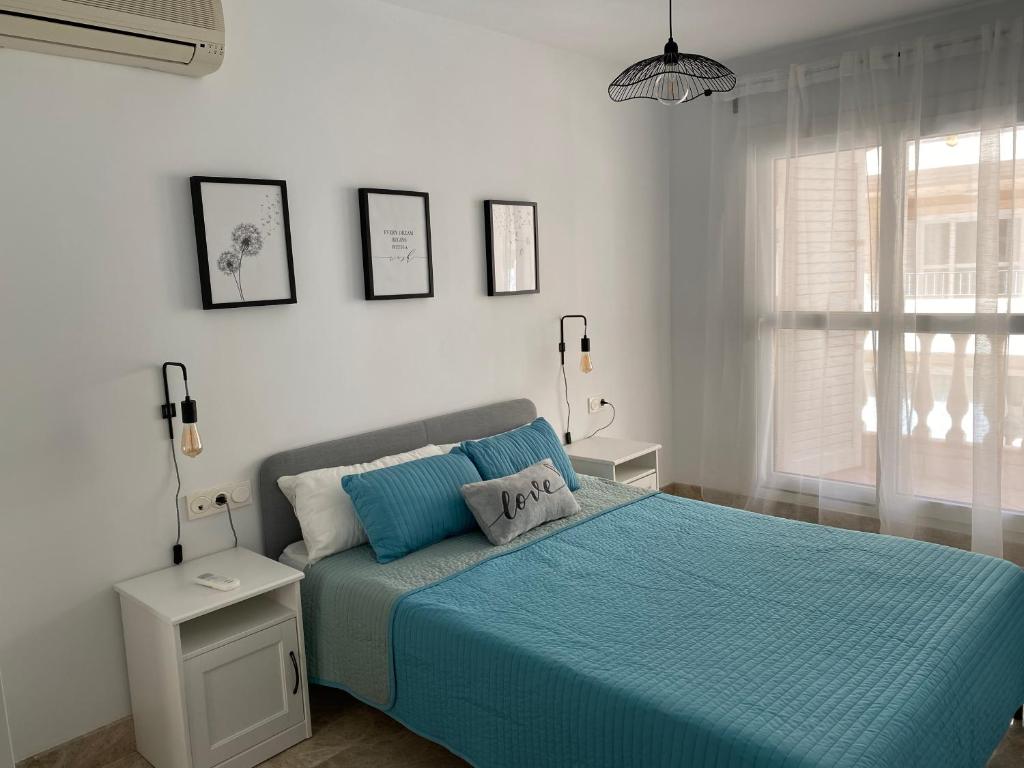 a bedroom with a bed with blue sheets and a window at Apartamento Aguamarina in Almerimar