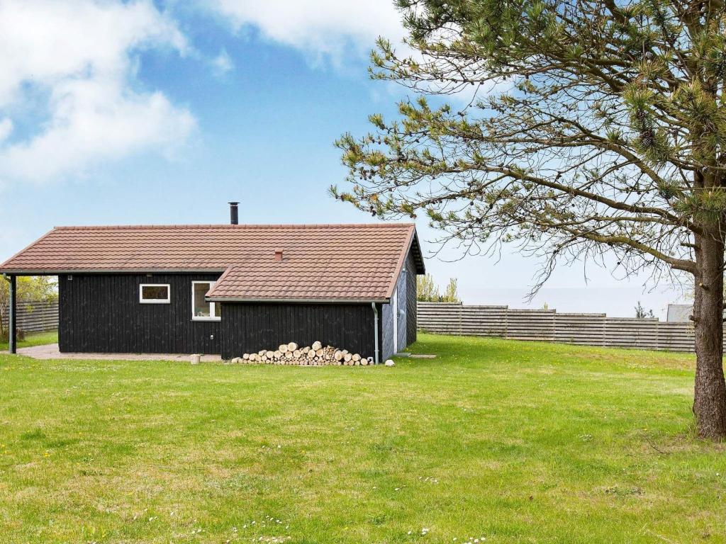 Ein schwarzes Haus auf einem Feld mit einem Baum in der Unterkunft 6 person holiday home in F revejle in Fårevejle