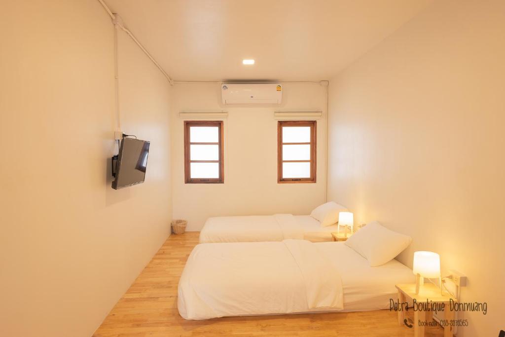 a bedroom with two beds and a tv in it at Petra Boutique Donmuang in Bangkok