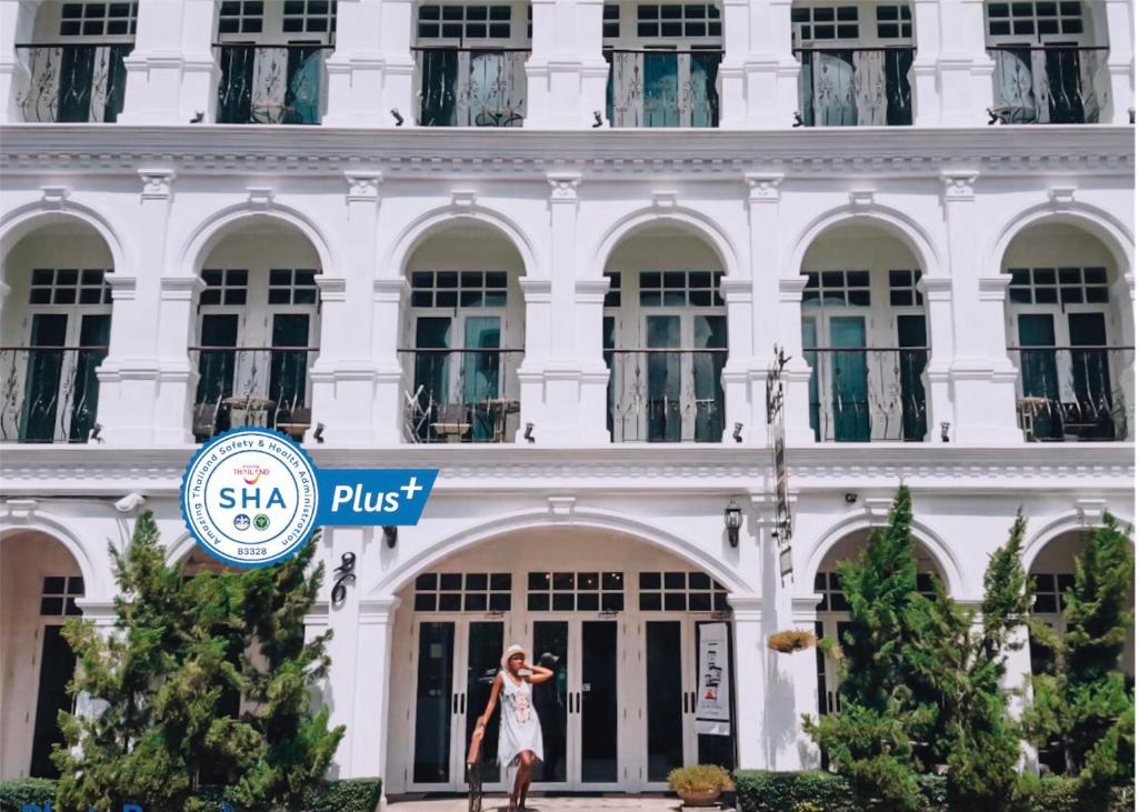een vrouw die voor een wit gebouw staat bij Casa Blanca Boutique Hotel - SHA Plus in Phuket