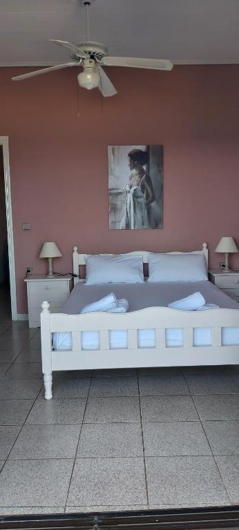 a white bed in a room with a ceiling fan at Bousounis Apartments in Chrani