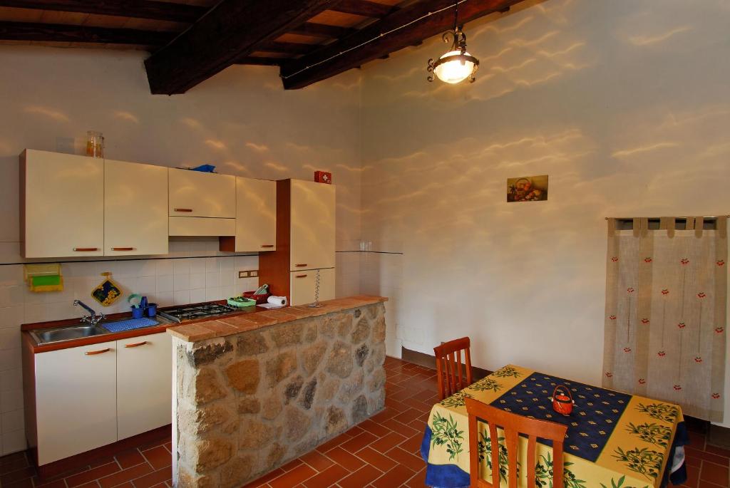 a kitchen with white cabinets and a table and a counter at AGRITURISMO LA PIAGGIA appartamenti a Vivo D'Orcia in Vivo dʼOrcia