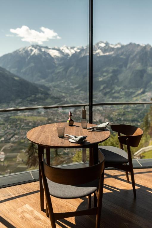 a wooden table and chairs on a balcony with mountains at Miramonti Boutique Hotel in Avelengo