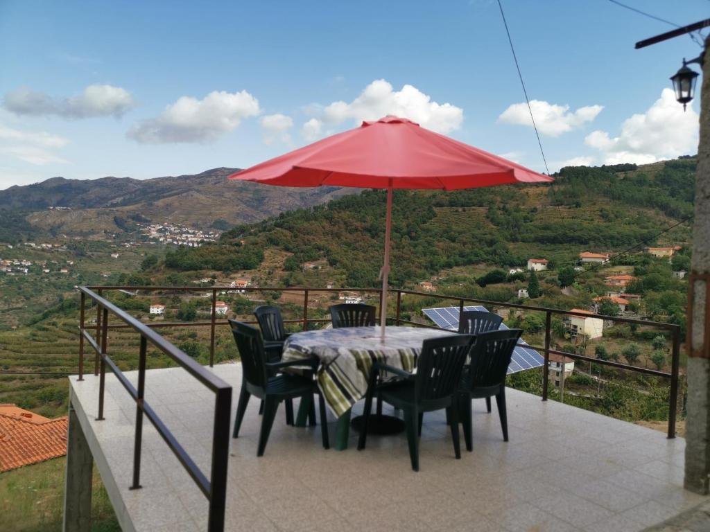 a table with chairs and a red umbrella on a balcony at Casa do Lagar in Resende