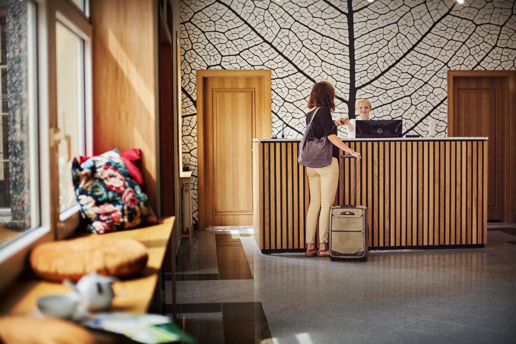 uma mulher parada num balcão com a sua bagagem em Park Hotel em Świdnica