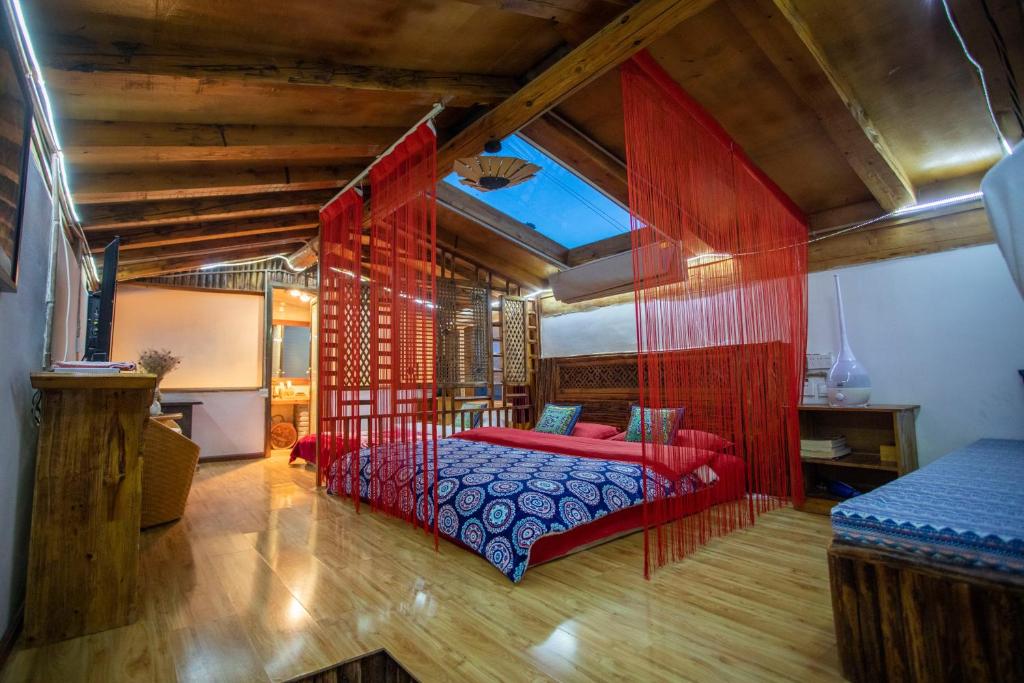 a bedroom with a red bed and wooden ceilings at Shangri-La King Gesar Guesthouse in Shangri-La
