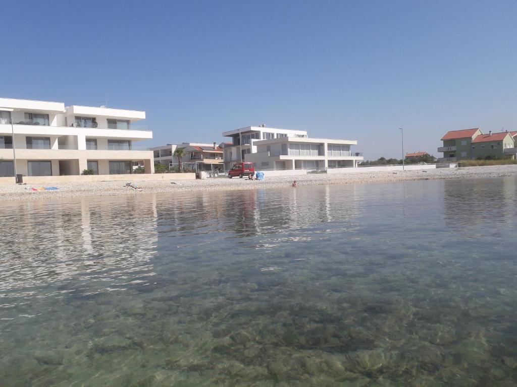 スコシャンにあるApartments Mirjanaの建物と水辺のビーチの景色を望めます。