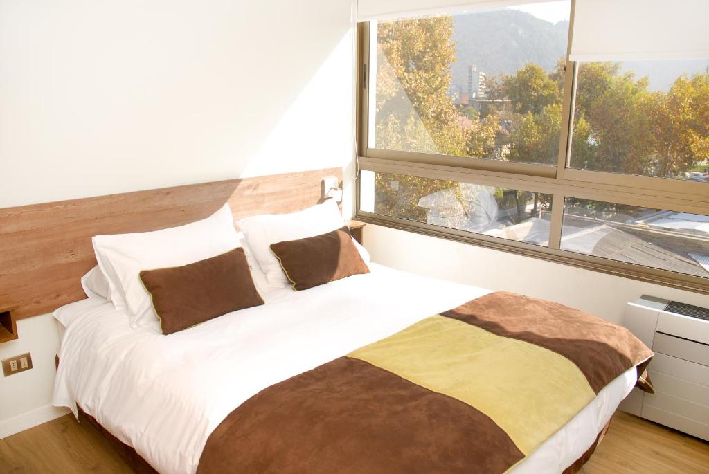 1 dormitorio con 1 cama grande y ventana grande en Apart Hotel Providencia, en Santiago