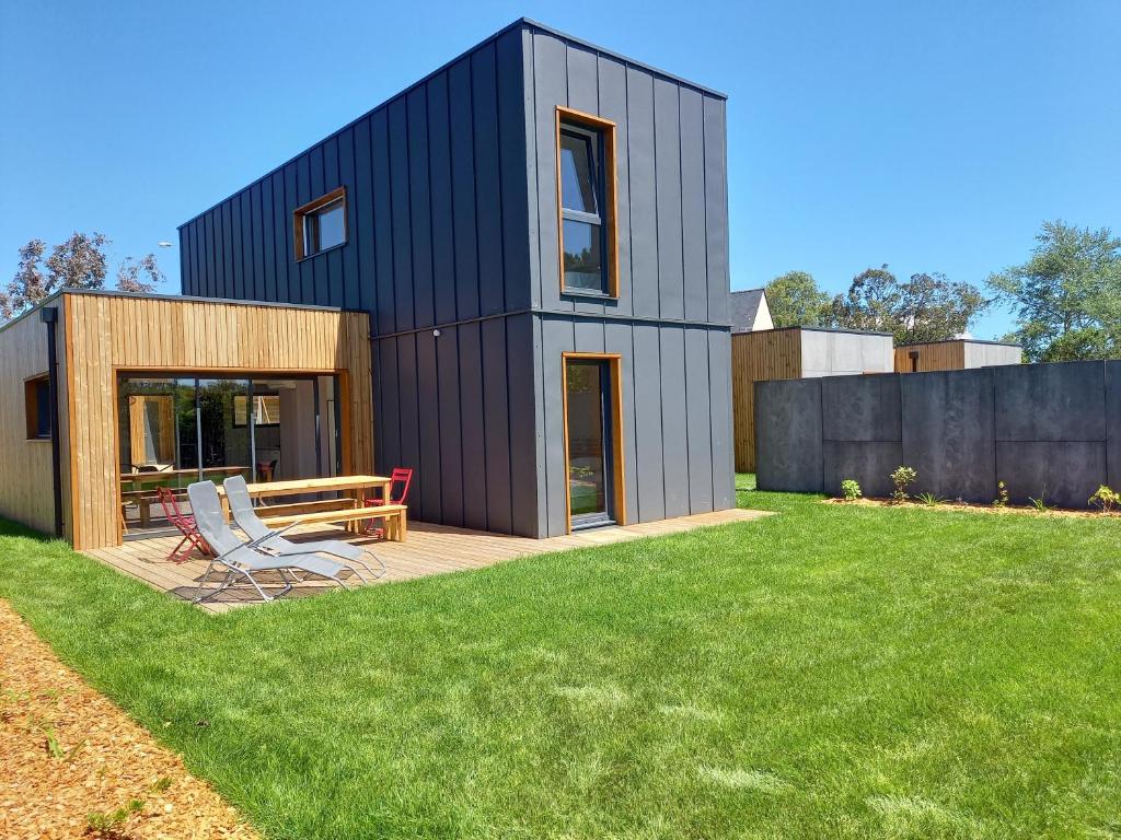 una casa negra con terraza y 2 sillas en Les Lodges de Beg Leguer - côte de granit rose, en Lannion