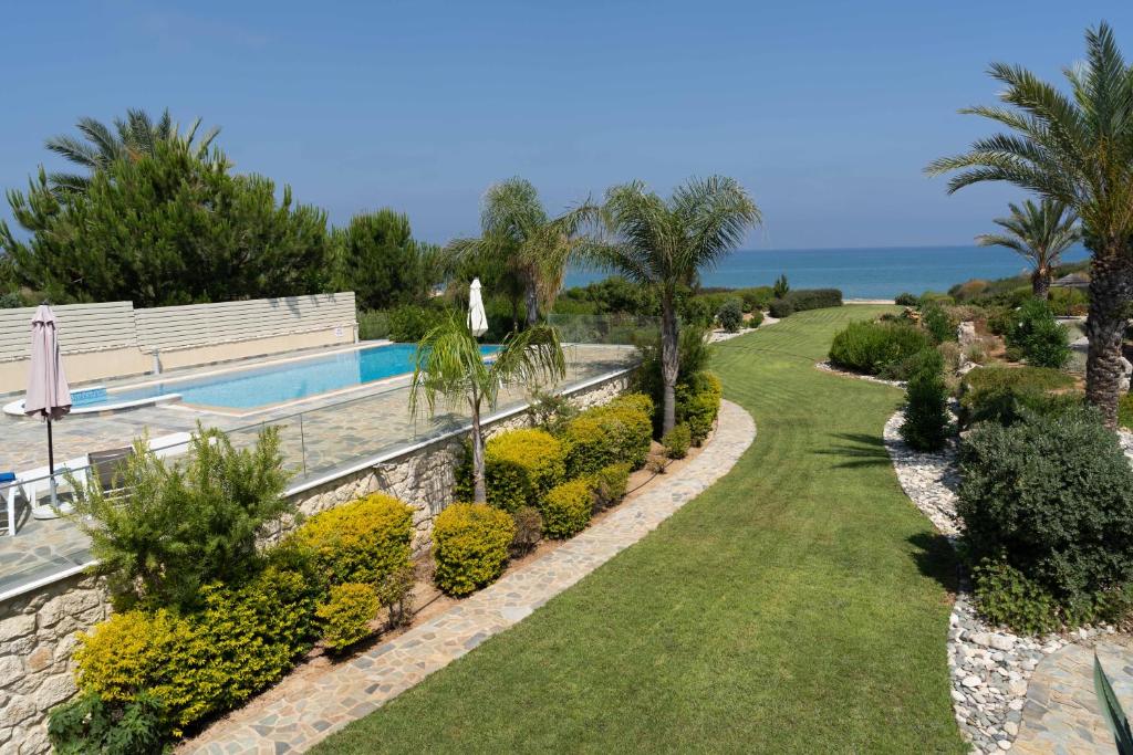 un giardino con piscina e l'oceano di Villa Harmonia - 4 Bedroom Luxury Beach Front Villa with Private Pool a Polis Chrysochous