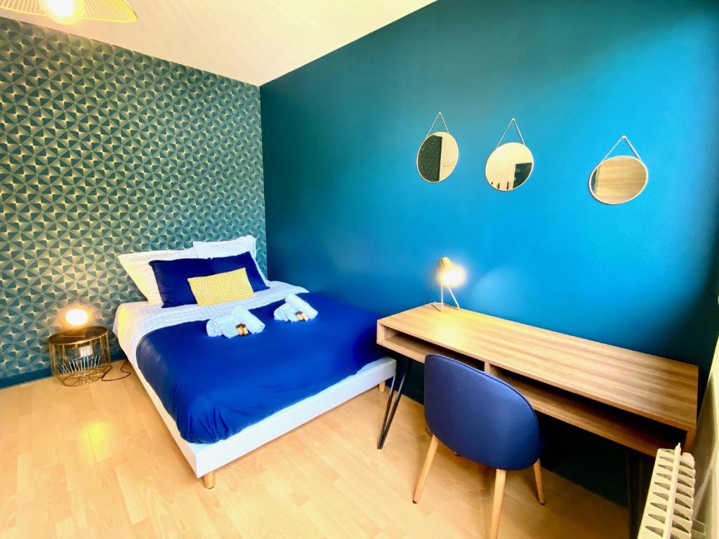 a blue bedroom with a bed and a wooden desk at Saturne YourHostHelper in Caen