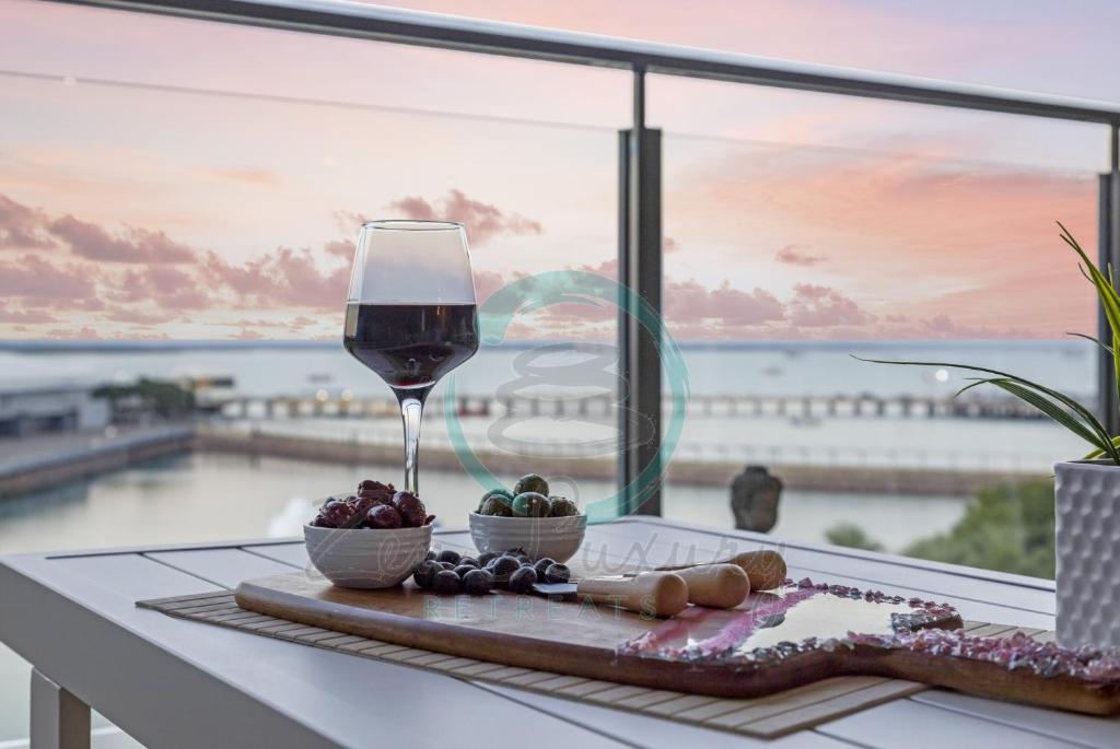 a glass of wine on a table with a view of the ocean at ZEN PENINSULA - Darwin's Prestigious WaterFront Retreat in Darwin