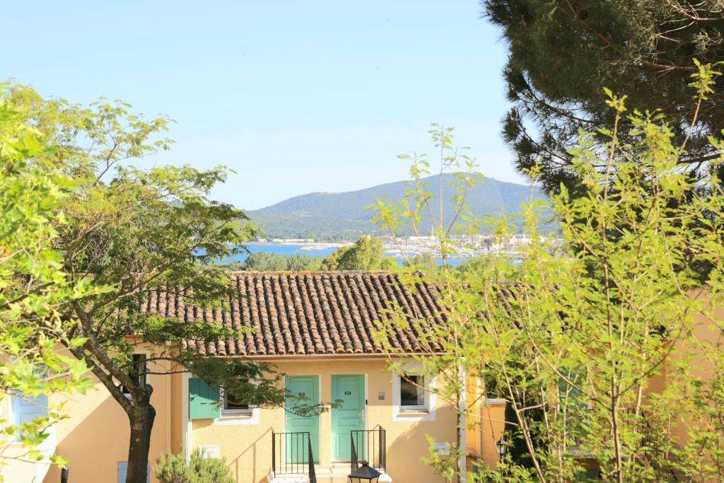 une maison jaune avec une porte bleue et des arbres dans l'établissement Chez Adriana Studio VUE MER avec Piscine, à Grimaud