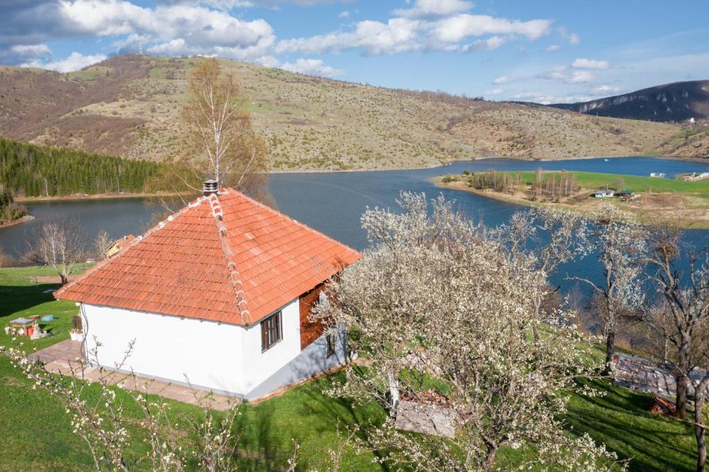 an old house with an orange roof next to a lake at Uvac Griffon in Nova Varoš