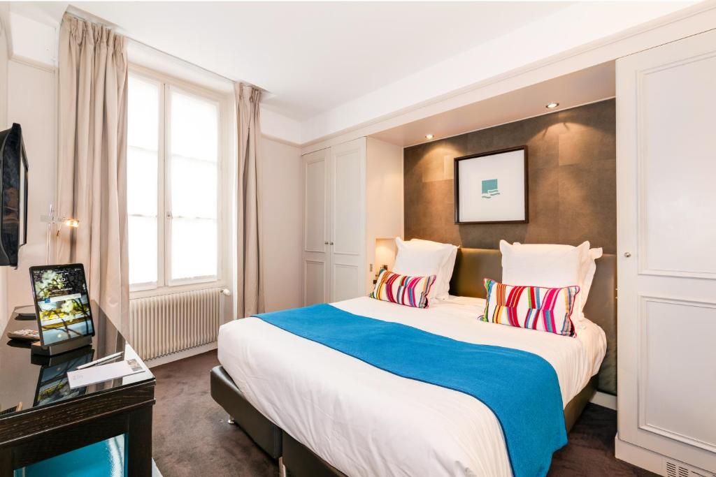ein Hotelzimmer mit einem großen Bett und einem TV in der Unterkunft Hôtel Duo in Paris