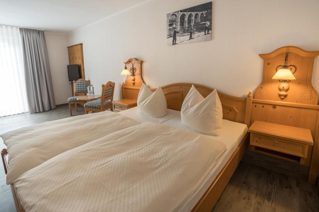 a bedroom with a large bed with white sheets at Hotel Willinger Mitte in Willingen