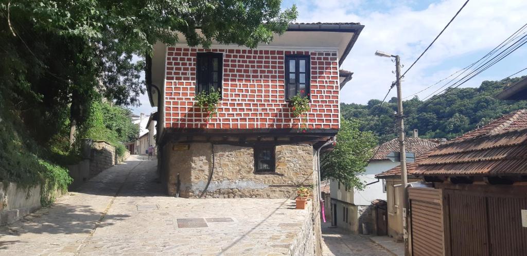 a brick building with two windows on a street at The Red Konak in Veliko Tŭrnovo