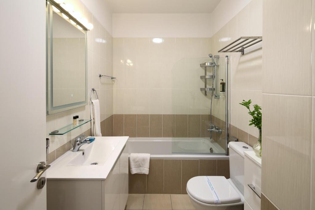 a bathroom with a tub and a sink and a toilet at Elysia Park in Paphos