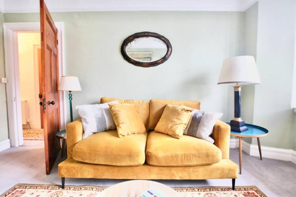 a living room with a yellow couch and a mirror at The View in Bowness-on-Windermere