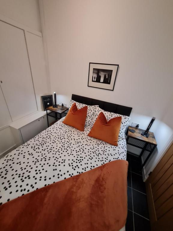 ein Schlafzimmer mit einem Bett mit zwei orangefarbenen Kissen in der Unterkunft No.8 in Stornoway