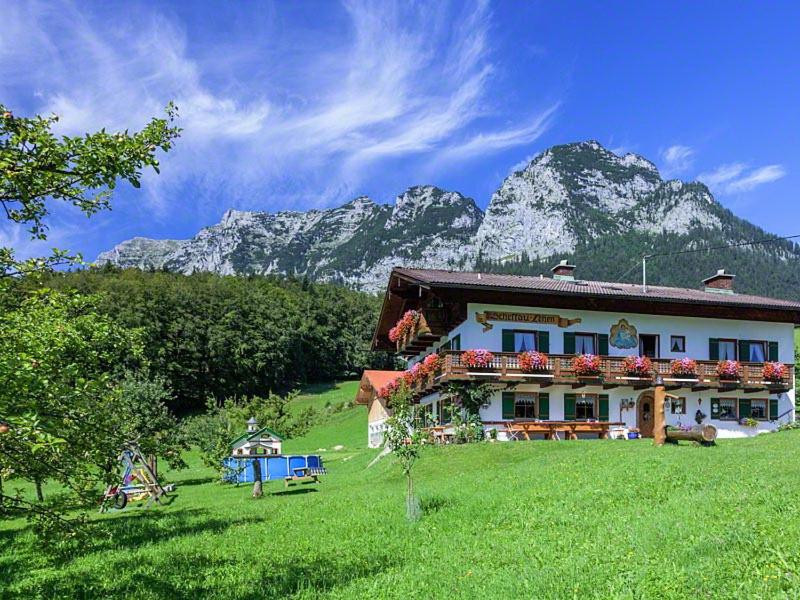 una casa en un campo con montañas en el fondo en Scheffaulehen Ferienwohnungen en Ramsau