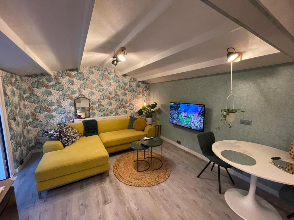 a living room with a yellow couch and a table at Tiny House de Eikhof in Hengelo