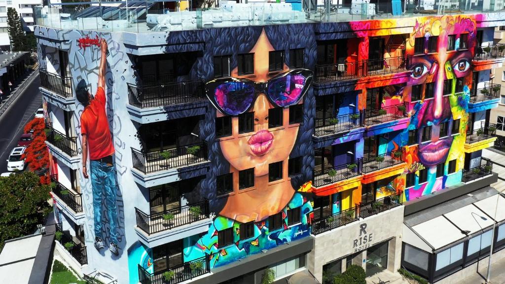 a building with a painting of a face with sunglasses on it at Rise Street Art Hotel in Larnaka