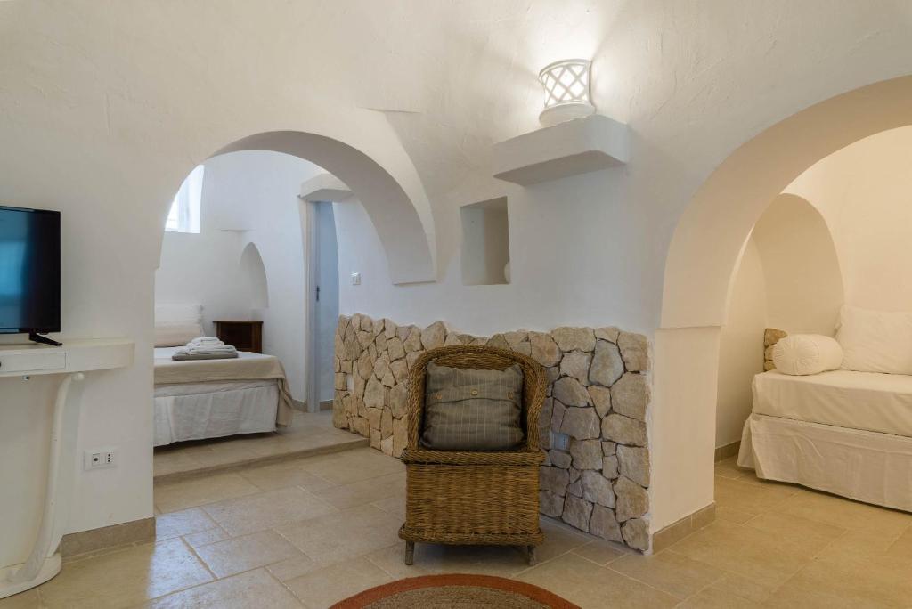 un salon avec une cheminée en pierre et une télévision dans l'établissement Charming Villas - Villa d'Itria with trullo, à Ostuni