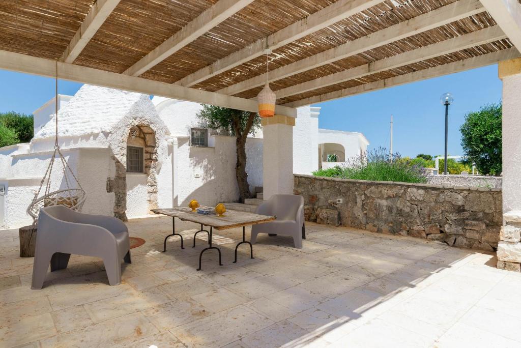 un patio avec une table et des chaises sous un toit dans l'établissement Charming Villas - Villa d'Itria with trullo, à Ostuni