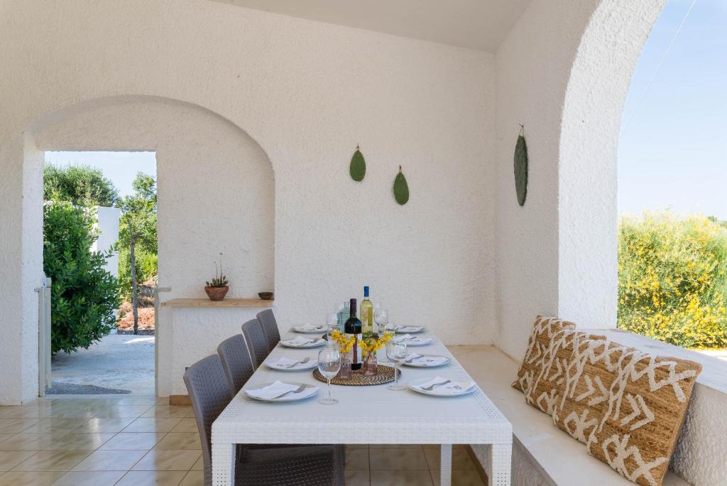 une salle à manger blanche avec une table et des chaises blanches dans l'établissement Charming Villas - Villa d'Itria with trullo, à Ostuni