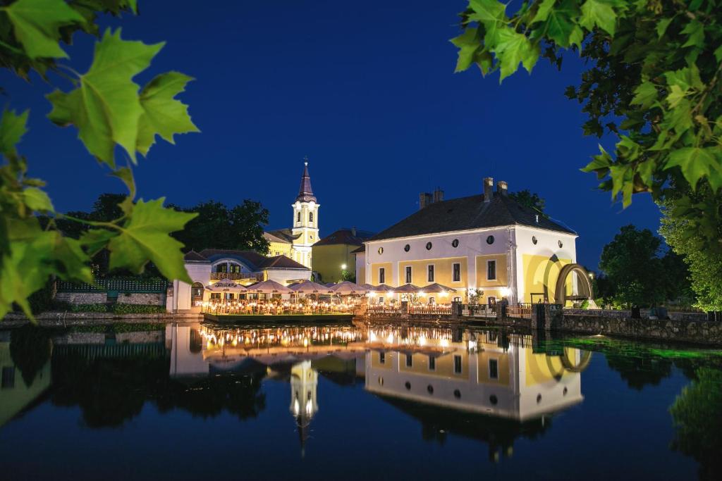 a building with a reflection in the water at night at Hotel Gabriella in Tapolca