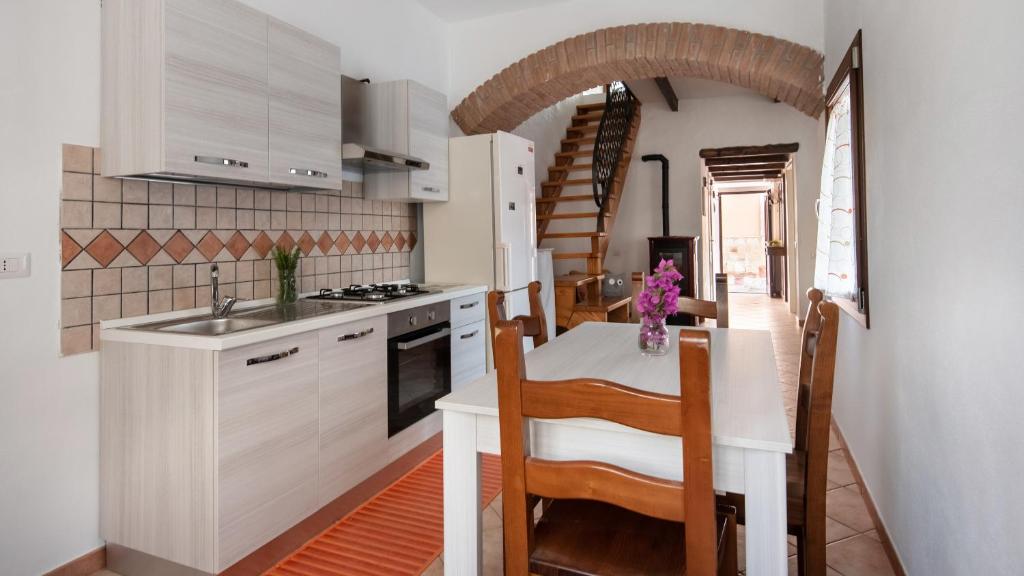 une cuisine avec des placards blancs et une table avec des chaises dans l'établissement Welcomely - La Casa di Annetta, à Gonnesa