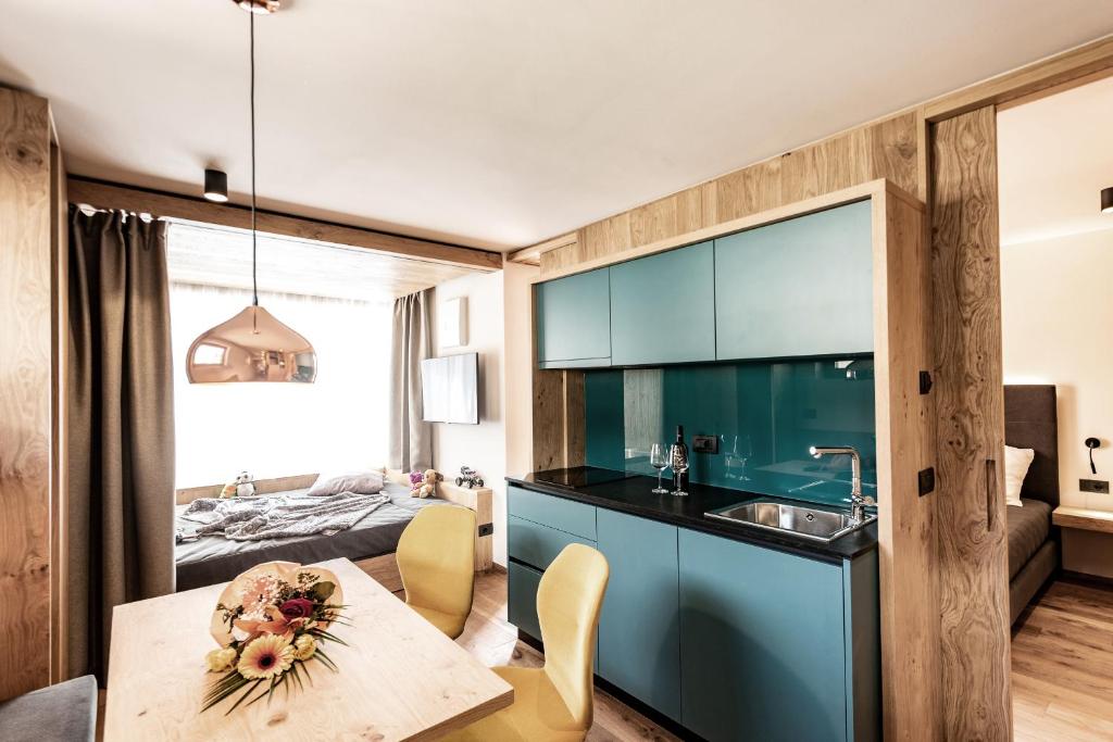 een keuken met blauwe kasten en een tafel in een kamer bij Mysciliar Apartment Sky I in Siusi