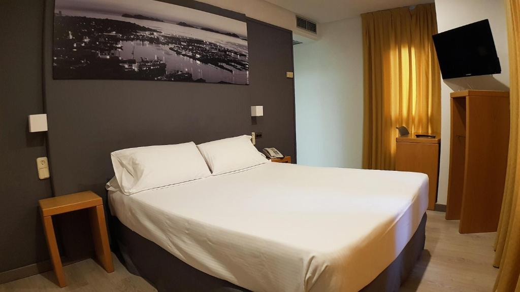 a bedroom with a large white bed and a television at Hotel del Mar Vigo in Vigo