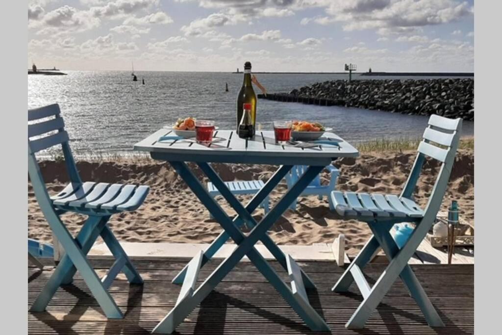 a picnic table with a bottle of wine and two chairs at Beachhouse direct aan zee in IJmuiden