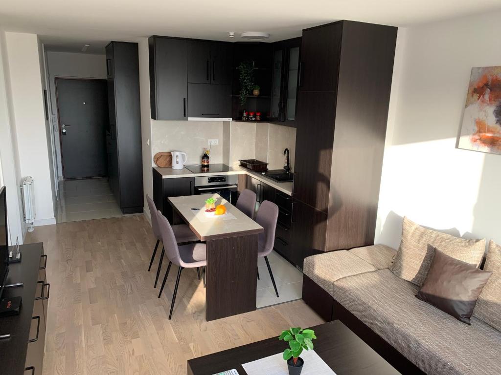 a kitchen and a living room with a table and a couch at Apartman Jasmin - Blizu Panonskih jezera i centra grada in Tuzla