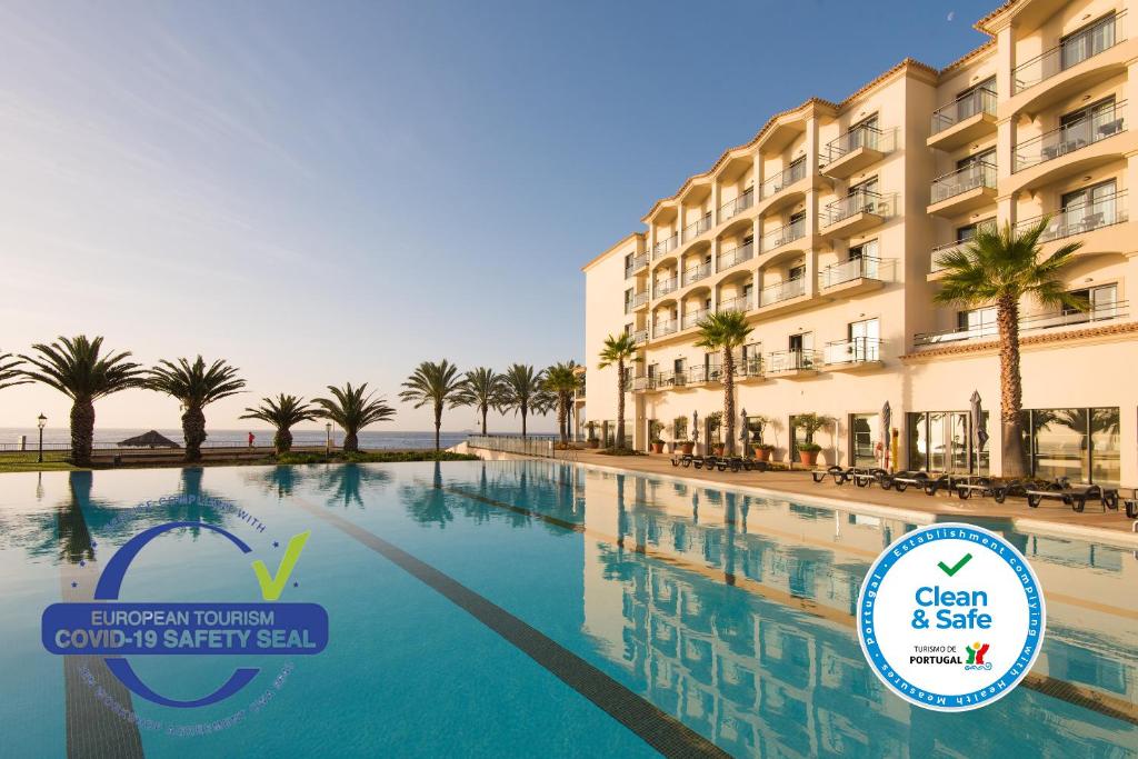 une piscine avec des palmiers en face d'un hôtel dans l'établissement Vila Gale Santa Cruz, à Santa Cruz