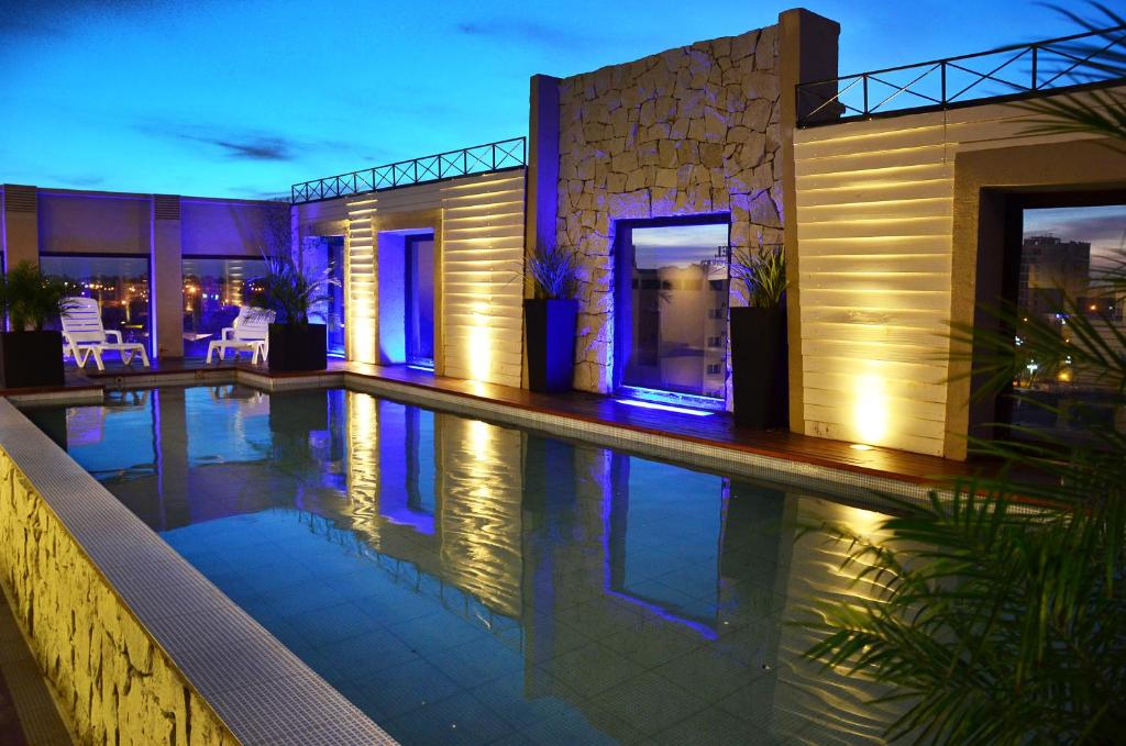 una casa con piscina por la noche en Le Parc Hotel & Suite en Villa María