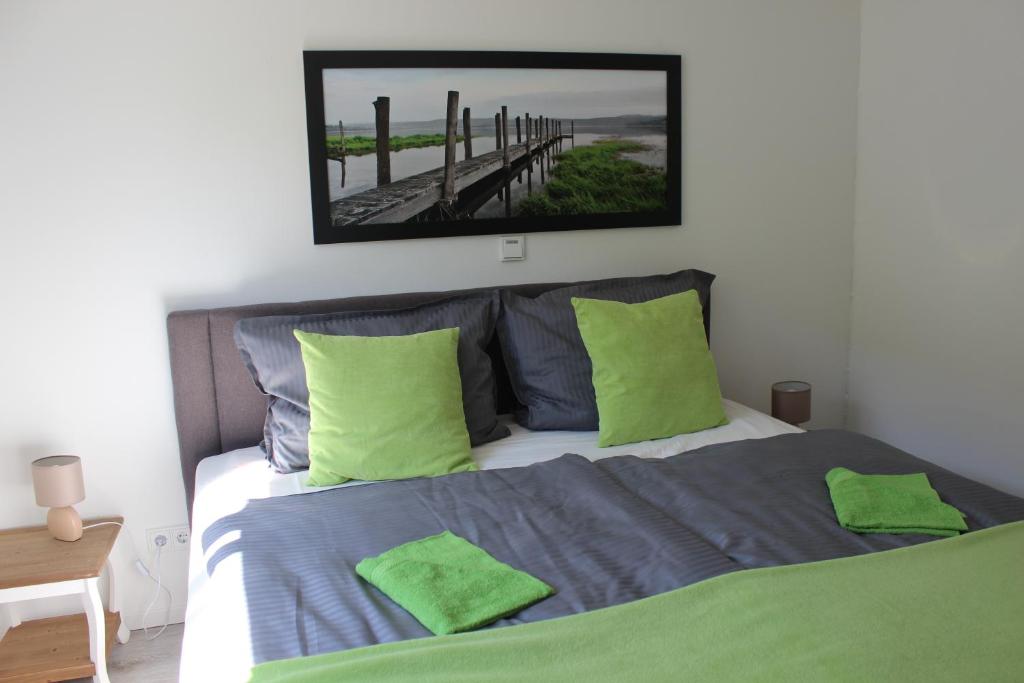 um quarto com uma cama com almofadas verdes e um espelho em FeWo Waldblick em Rieden