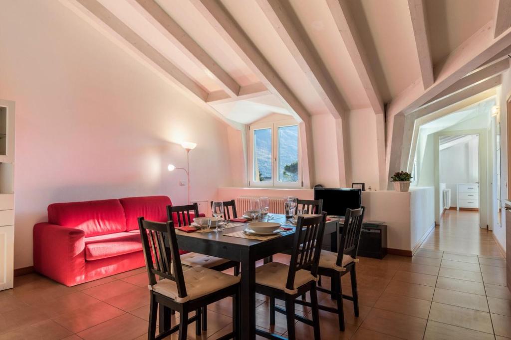 - une salle à manger avec une table et un canapé rouge dans l'établissement Appartamento Villa Principessa, à Arco