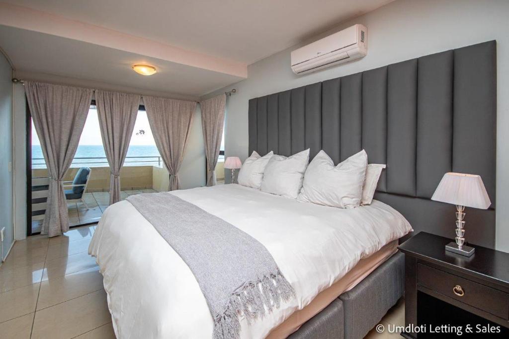 una camera da letto con un grande letto con una parete grigia di Lazy Lizard 41 - with Inverter a Umdloti