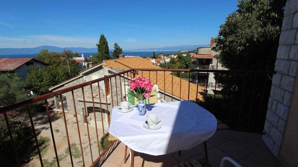 een witte tafel met bloemen op een balkon bij Apartments Tonica in Malinska